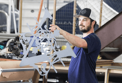 Man holding a large metal snowflake sculpture in an industrial setting