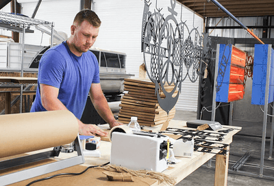 Man working with paper and a cutting machine in a workshop setting